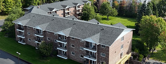 A large apartment complex with multiple buildings and a parking lot in front.