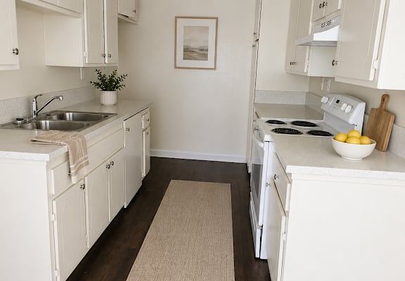 A kitchen with white cabinets and a beige rug on the floor.
