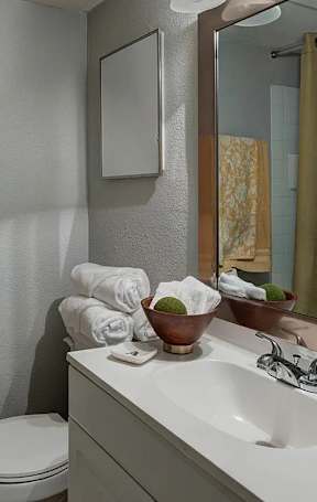 A bathroom with a toilet, sink, mirror, and a towel hanging on the wall.
