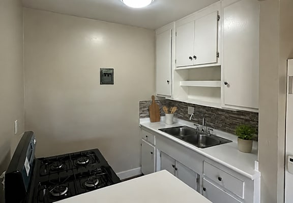 A small kitchen with a black stove top and white cabinets.