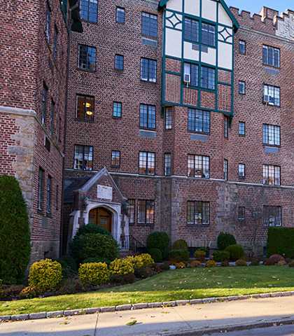 a large brick building with many windows and a green lawn in front of it