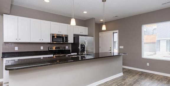a kitchen with white cabinets and a black counter top at 5Fifty5, Des Moines, IA 50309