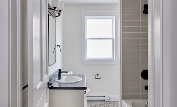 A bathroom with a sink, mirror, and a window.