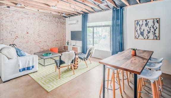 A living room with a white couch, a wooden table, and a green rug.
