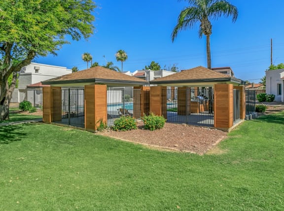 A house with a brown roof and glass walls is surrounded by a green lawn.