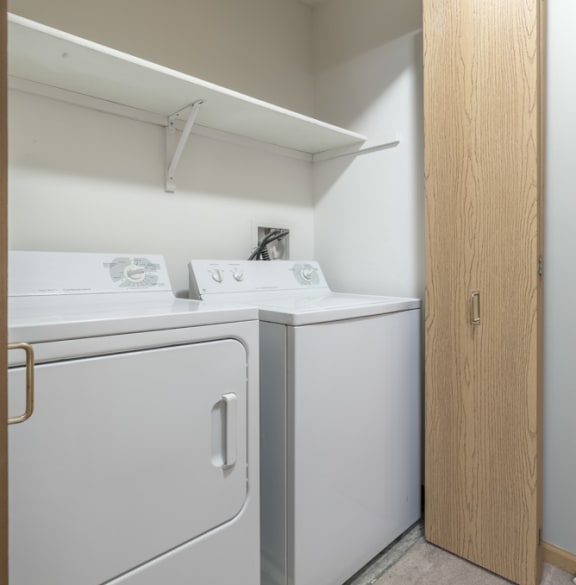 a full size washer and dryer in a double door closet with overhead storage