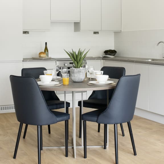 a dining area with a table and chairs and a kitchen with white cabinets