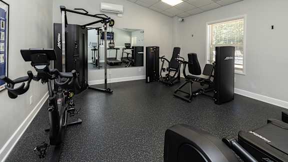 A gym with a treadmill, weights, and exercise machines.