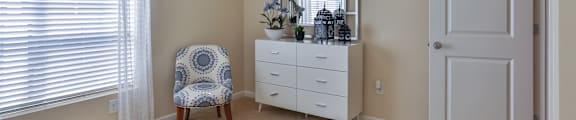 A bedroom with a bed, chair, and dresser.