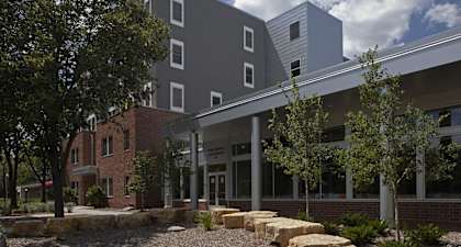 a large building with trees and rocks in front of it