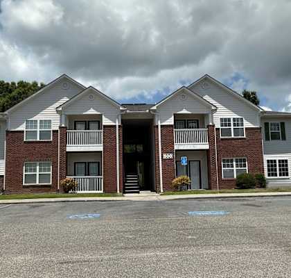 Two identical houses are situated in a parking lot.