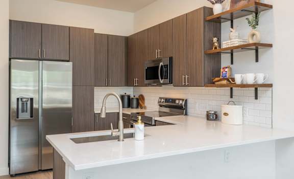 A modern kitchen with a white countertop and stainless steel appliances.