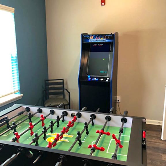 A foosball table is in a room with a video game machine.