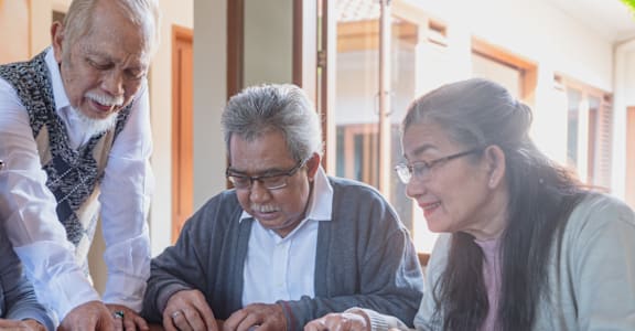 Three people are playing a game with jigsaw puzzle pieces.