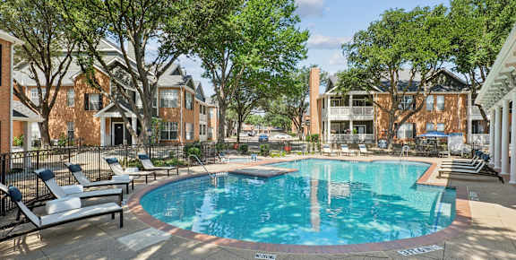 A swimming pool surrounded by trees and chairs in a residential area.
