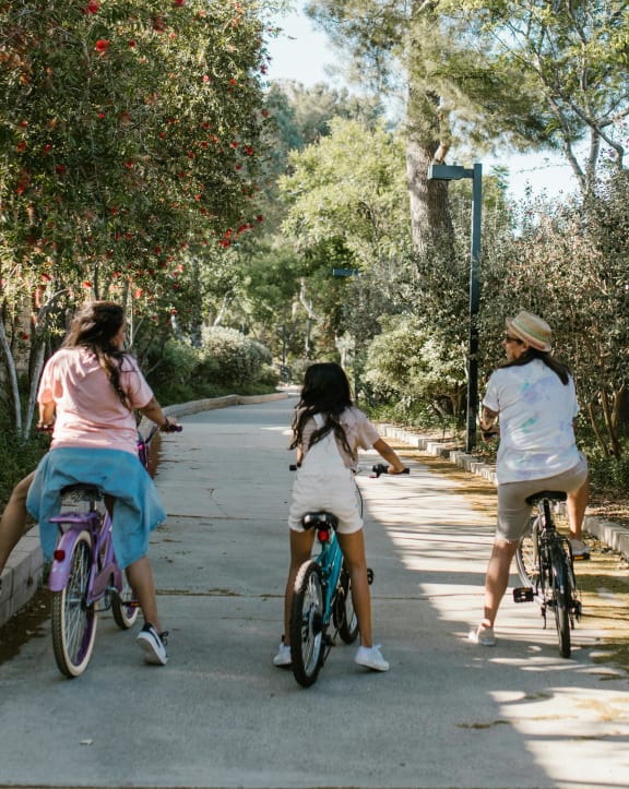 three girls riding bikes down a street