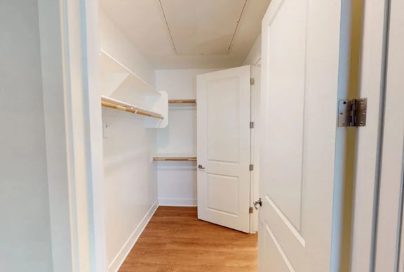 A white door is in a hallway with a wooden floor.