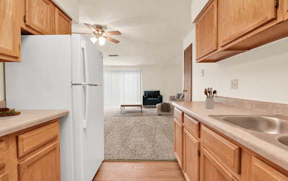 A kitchen with wooden cabinets and a white refrigerator. at Kimberly Club Apartments, Iowa, 52807