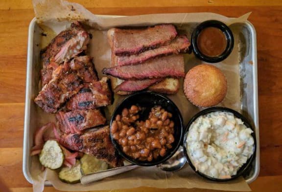 a tray of food with meat and sides on a table