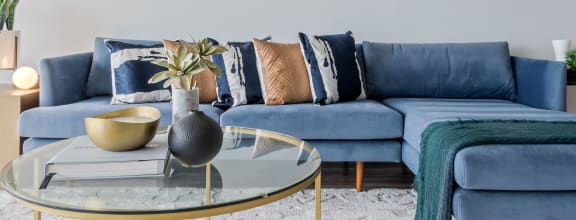 a living room with blue couches and a glass coffee table