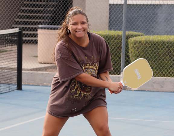 A woman is playing tennis on a blue court.