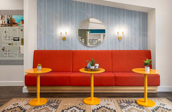 A red sofa with two yellow tables in front of it.