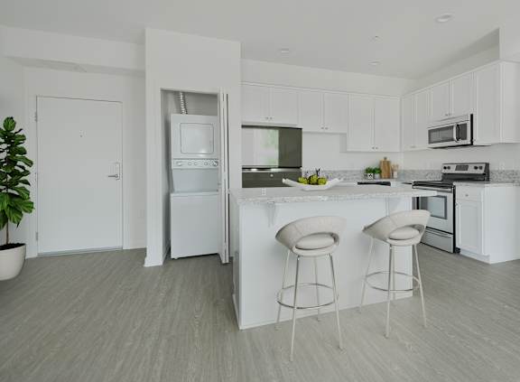 A white kitchen with a bar and stools.at 422 South Lake, Los Angeles, 90057