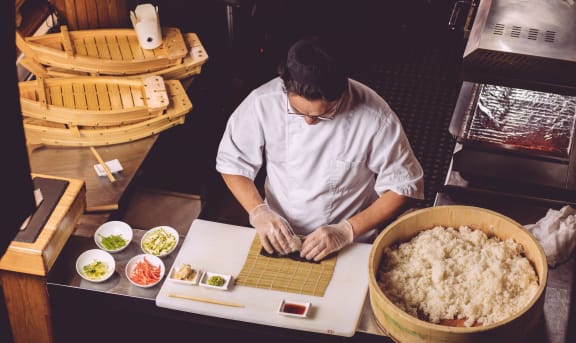 experienced chef preparing sushi in the kitchen. top viewus photo. man showing workout of preparing sushi