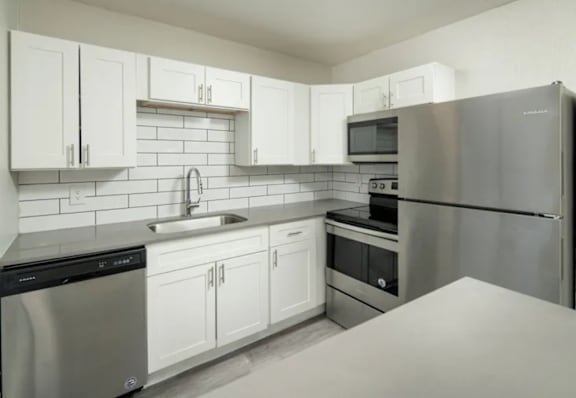 A kitchen with white cabinets and stainless steel appliances.