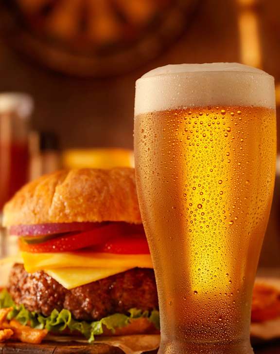 A glass of beer is in the foreground with a burger in the background at West Oak Apartments, North Carolina 27587
