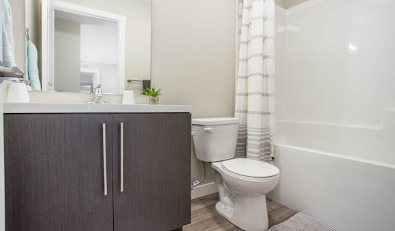 A white toilet sits next to a white bathtub in a bathroom.
