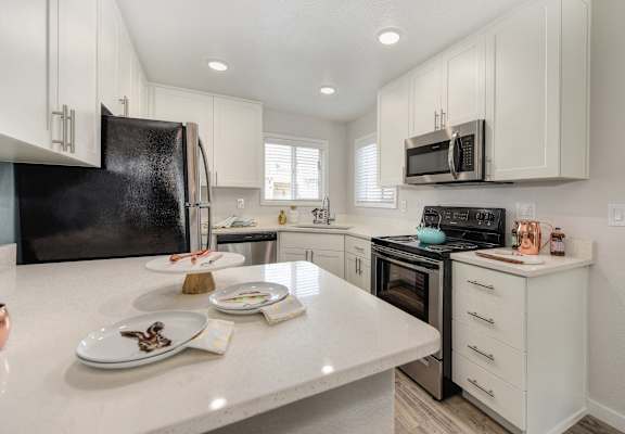 an open kitchen with white cabinets and a white counter top at The Legacy Apartments, California
