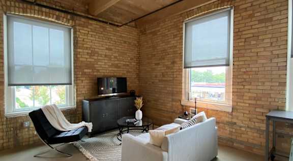 A living room with a white couch and a black chair.