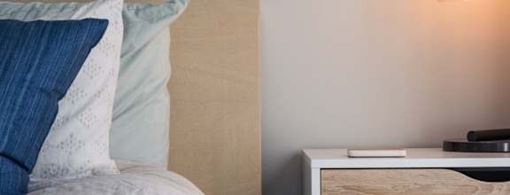 A bed with a white comforter and a lamp on a side table.