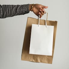 A hand holding a brown paper bag.