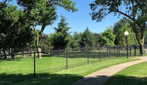 A park with a fence and a walking path.
