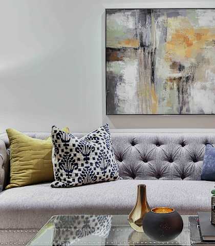 a living room with a gray couch and yellow and blue pillows