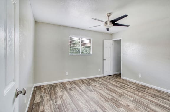 A room with a ceiling fan and a window with blinds.
