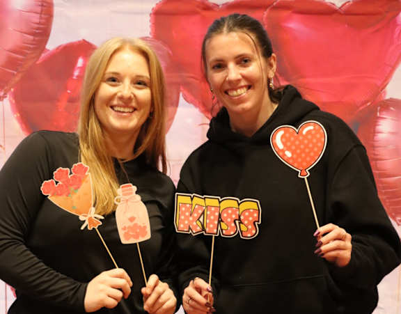 Two people wearing black outfits holding heart-shaped objects.