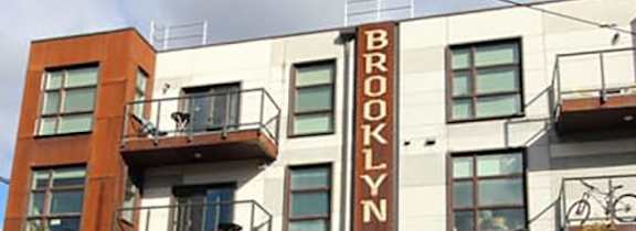 A white car is parked in front of a Brooklyn Road building.