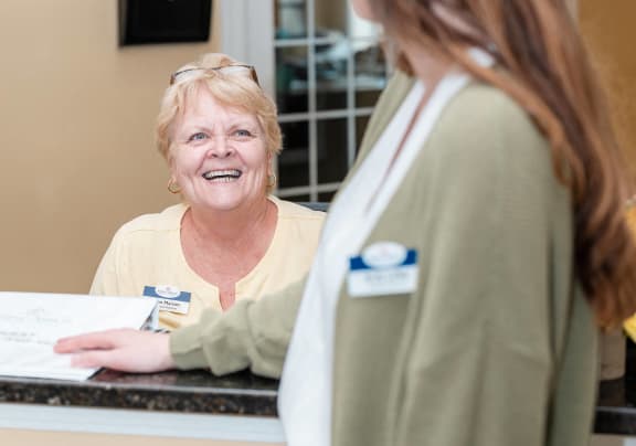 an older woman talking to a nurse in front of a desk