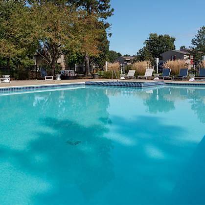 A large swimming pool surrounded by trees and chairs.