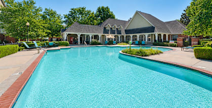 A large swimming pool in front of a building with a covered patio.
