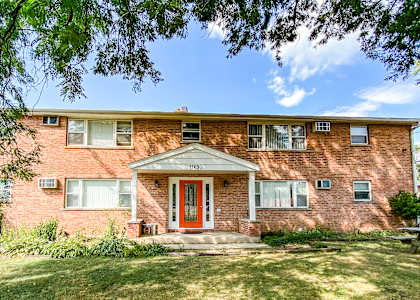 a brick house with a red door and a grass yard