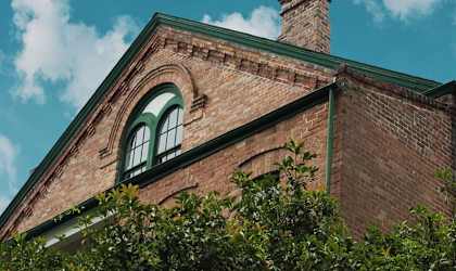 A brick building with a green window and a chimney.