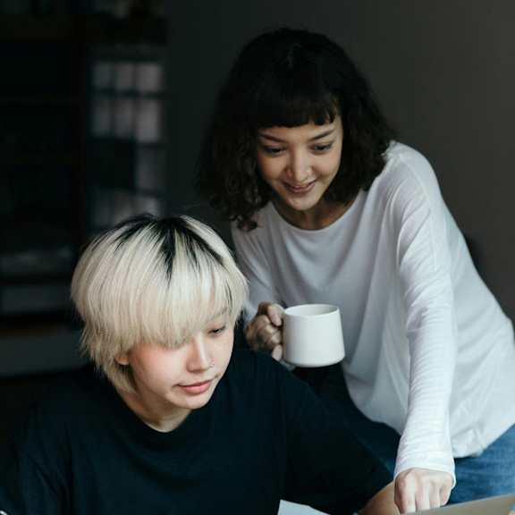 two people sitting at a table looking at a laptop computer