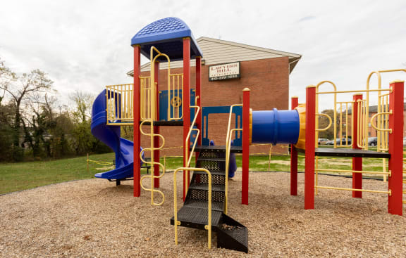 a playground with a blue and red slide and monkey bars at Lawyers Hill Apartments, Elkridge, MD, 21075