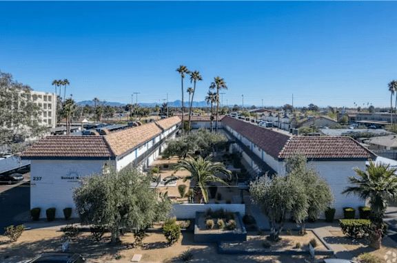 A building complex with palm trees in front.
