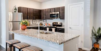 A kitchen with a granite countertop and bar stools.