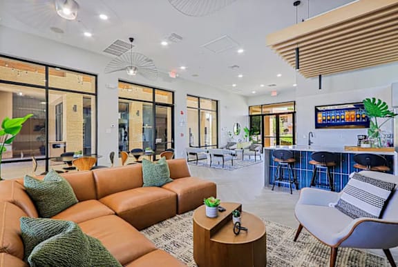A modern living room with a large orange sofa and a bar area with a TV.
